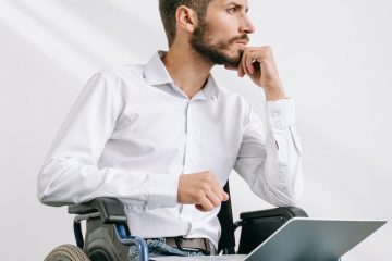 a man sitting on a wheelchair with a laptop on his lap